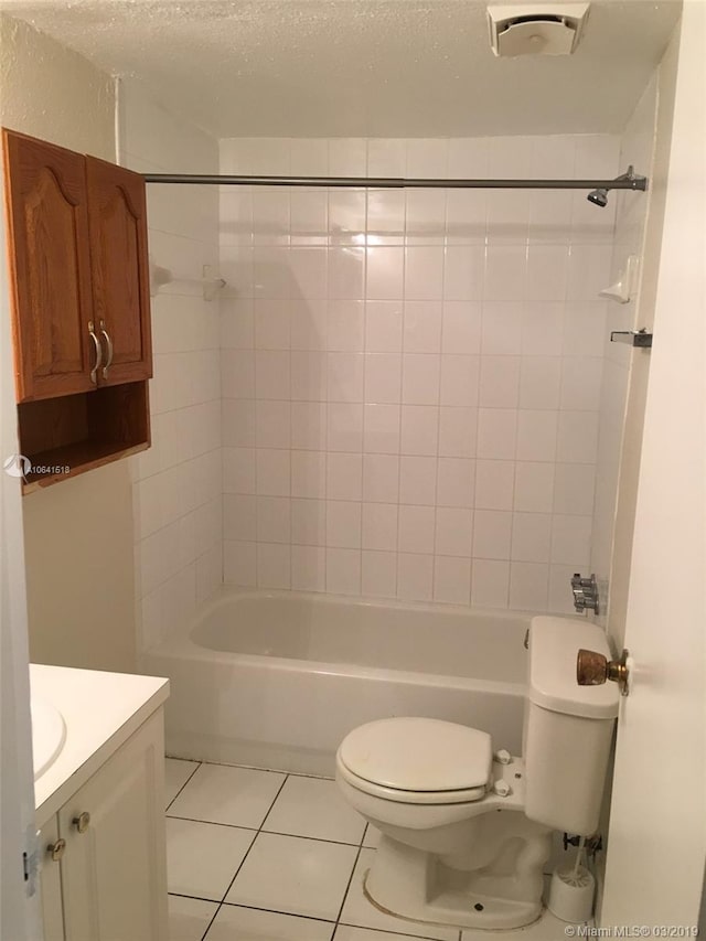 full bathroom with vanity, tile patterned flooring, a textured ceiling, tiled shower / bath, and toilet