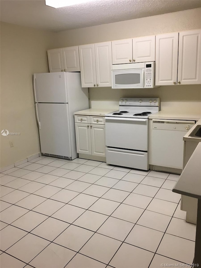 kitchen featuring light tile patterned floors, a textured ceiling, white appliances, and white cabinetry