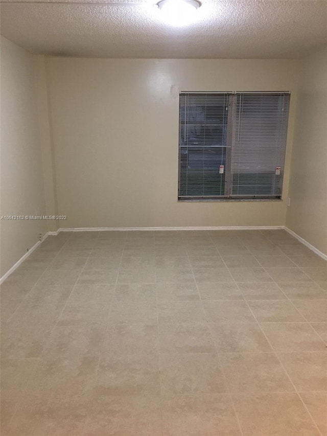 empty room featuring light tile flooring and a textured ceiling