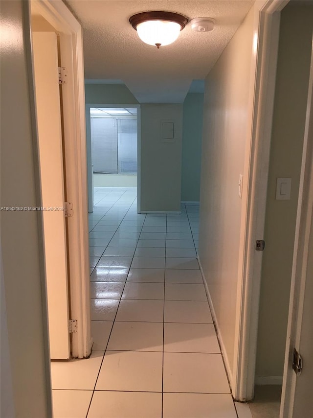 hall featuring light tile flooring and a textured ceiling