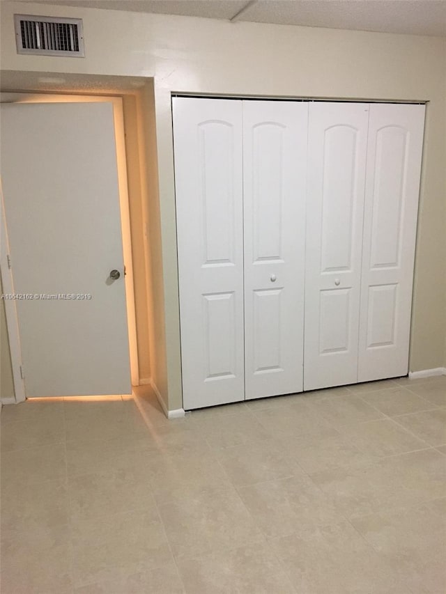 unfurnished bedroom featuring a closet and light tile floors