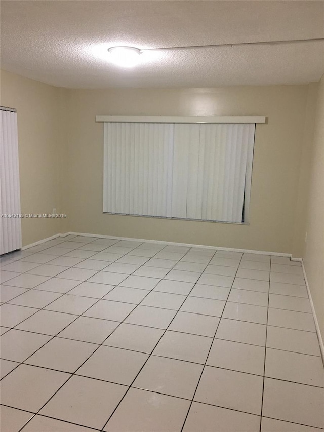 tiled spare room featuring a textured ceiling