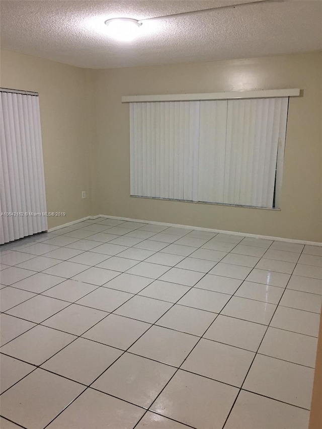 tiled empty room with a textured ceiling