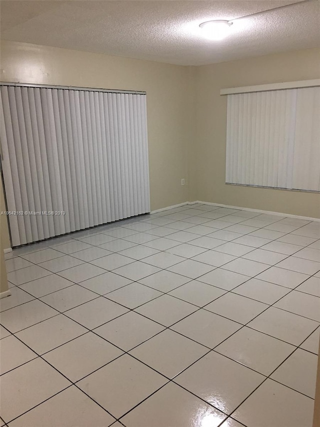 tiled empty room featuring a textured ceiling