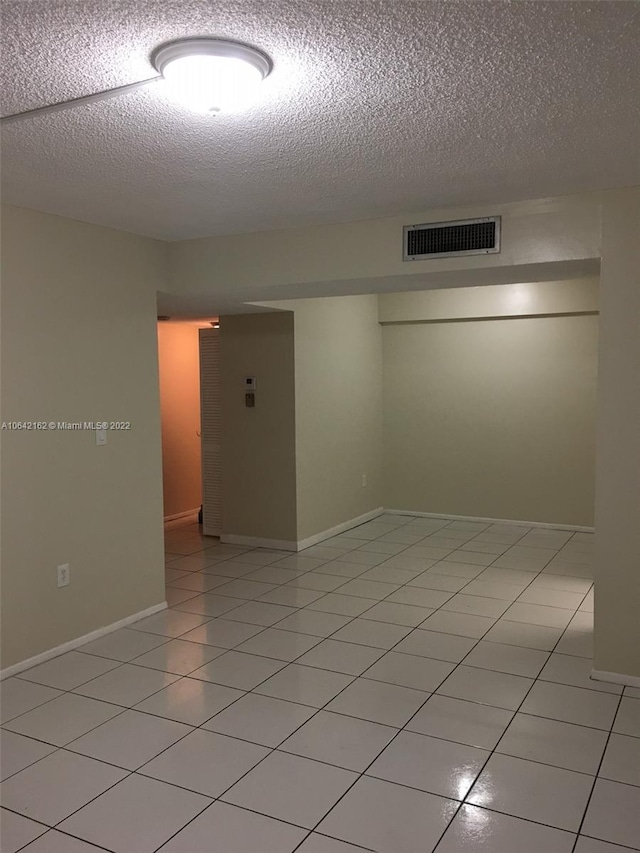 unfurnished room featuring a textured ceiling and light tile flooring