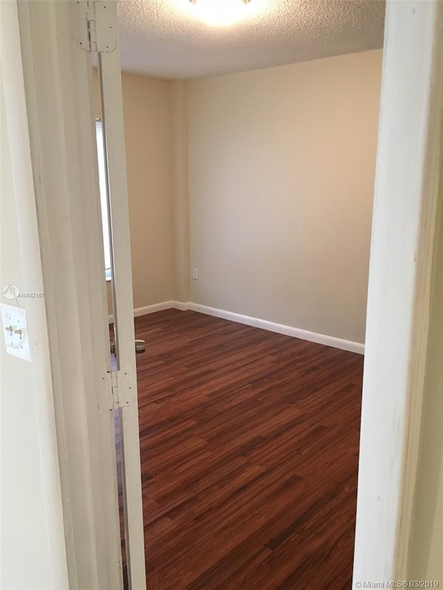 spare room with a textured ceiling and dark wood-type flooring