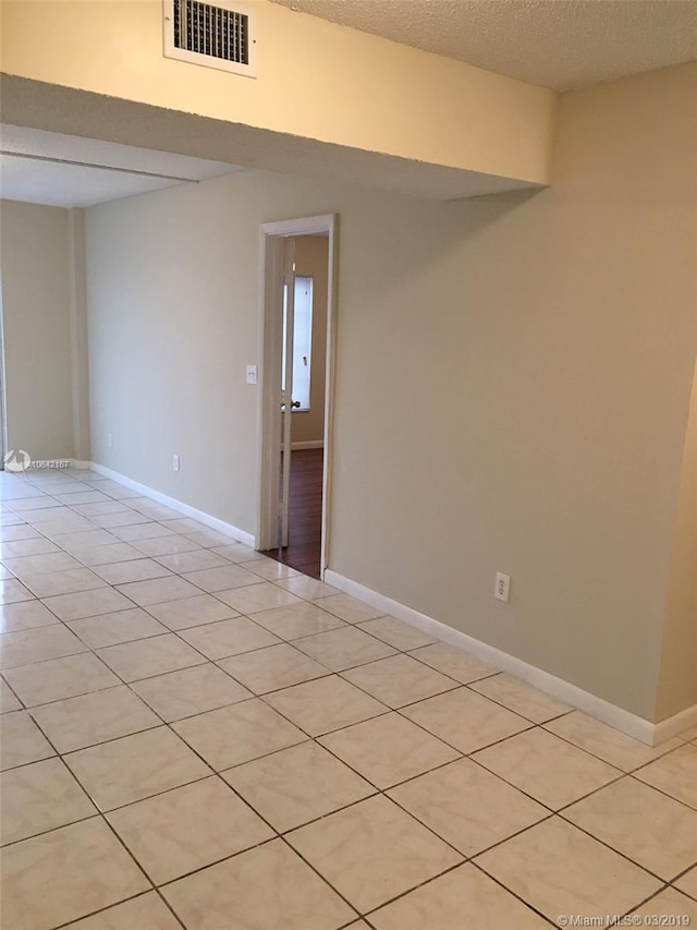 tiled spare room with a textured ceiling