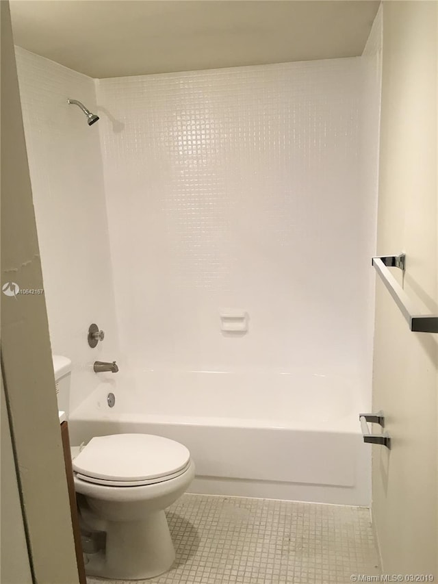 bathroom featuring shower / washtub combination, toilet, and tile flooring