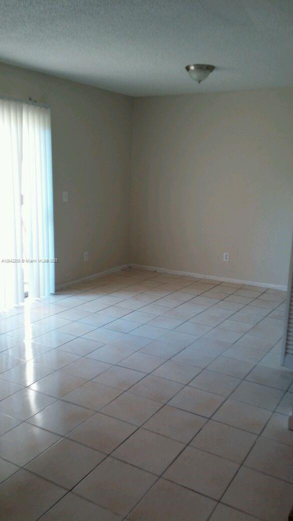 tiled empty room featuring a textured ceiling