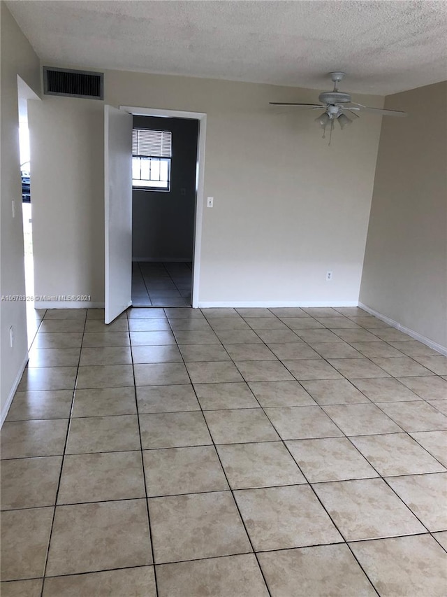 tiled spare room featuring a textured ceiling and ceiling fan