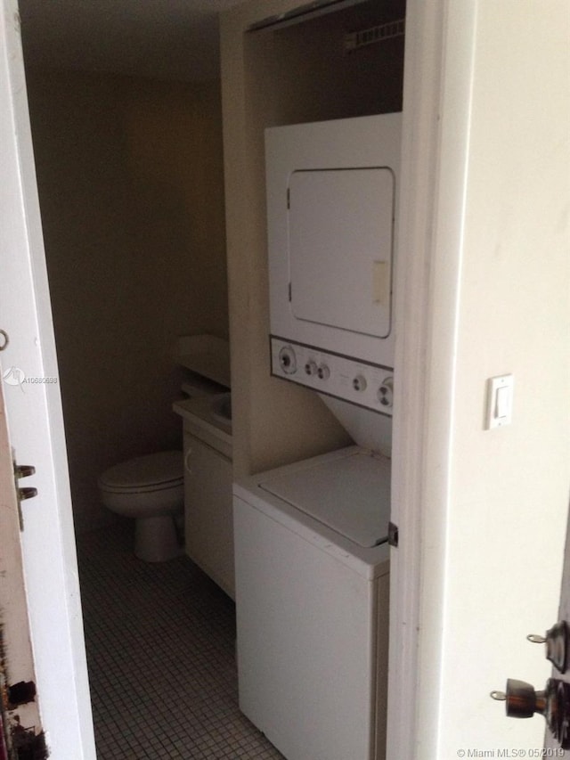 laundry area featuring tile flooring and stacked washer / dryer