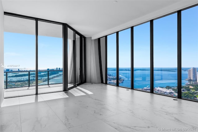 tiled spare room with a healthy amount of sunlight, expansive windows, and a water view