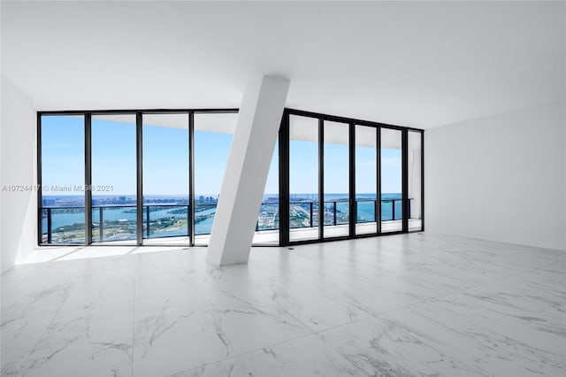 unfurnished room with light tile floors, floor to ceiling windows, and a water view