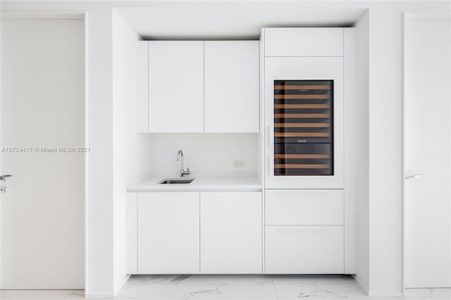 bar with wine cooler, white cabinetry, and sink