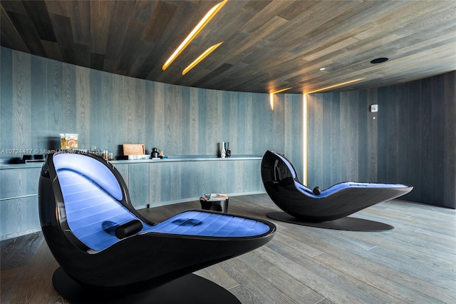 sitting room with wooden walls, wooden ceiling, and dark wood-type flooring