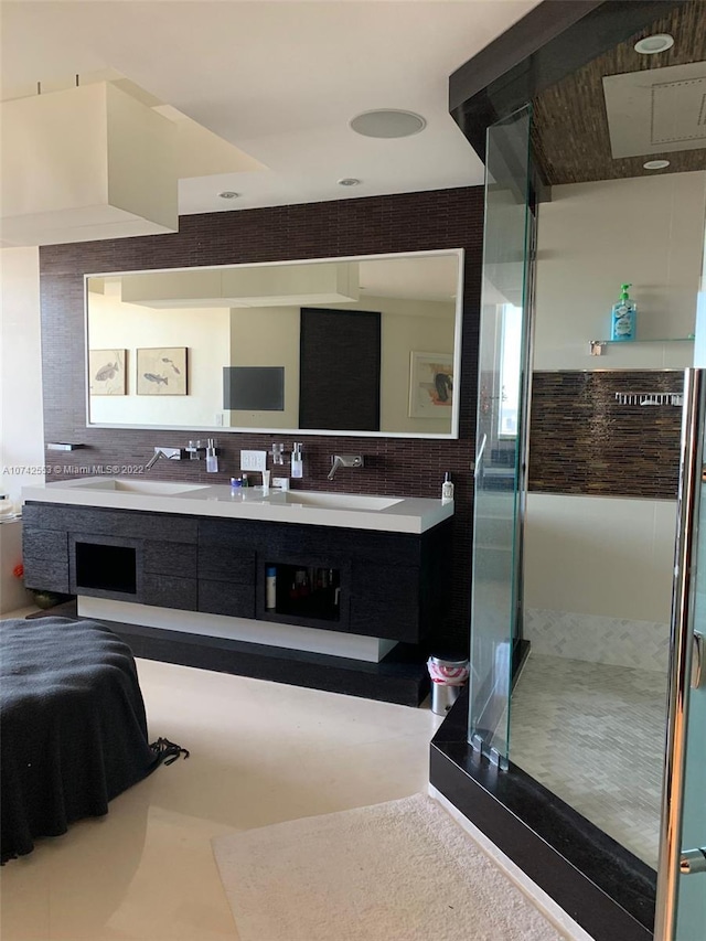 bathroom featuring dual vanity and a shower with shower door