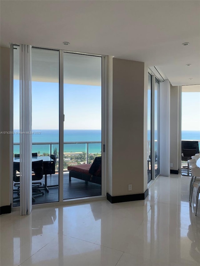 corridor with a water view, floor to ceiling windows, light tile floors, and french doors