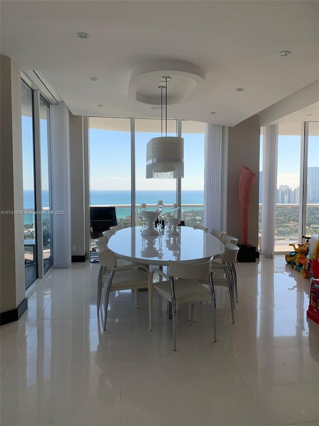 tiled dining room featuring a water view, french doors, and a wall of windows