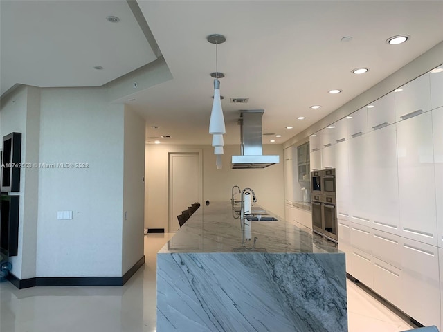 kitchen with white cabinets, exhaust hood, pendant lighting, and stone countertops