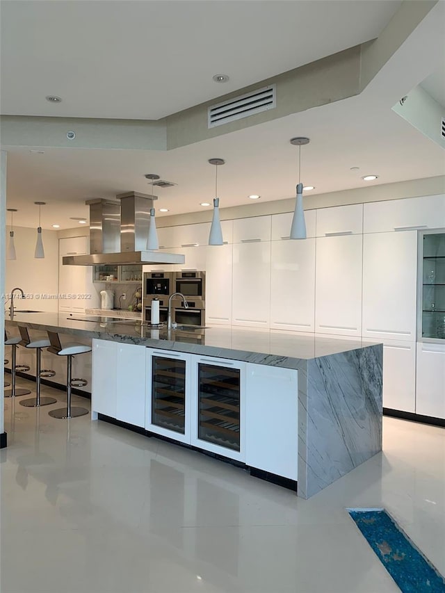 kitchen with wine cooler, white cabinetry, decorative light fixtures, and dark stone countertops