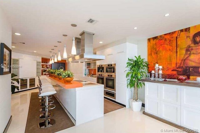 kitchen with island range hood, a center island, a kitchen bar, white cabinetry, and hanging light fixtures