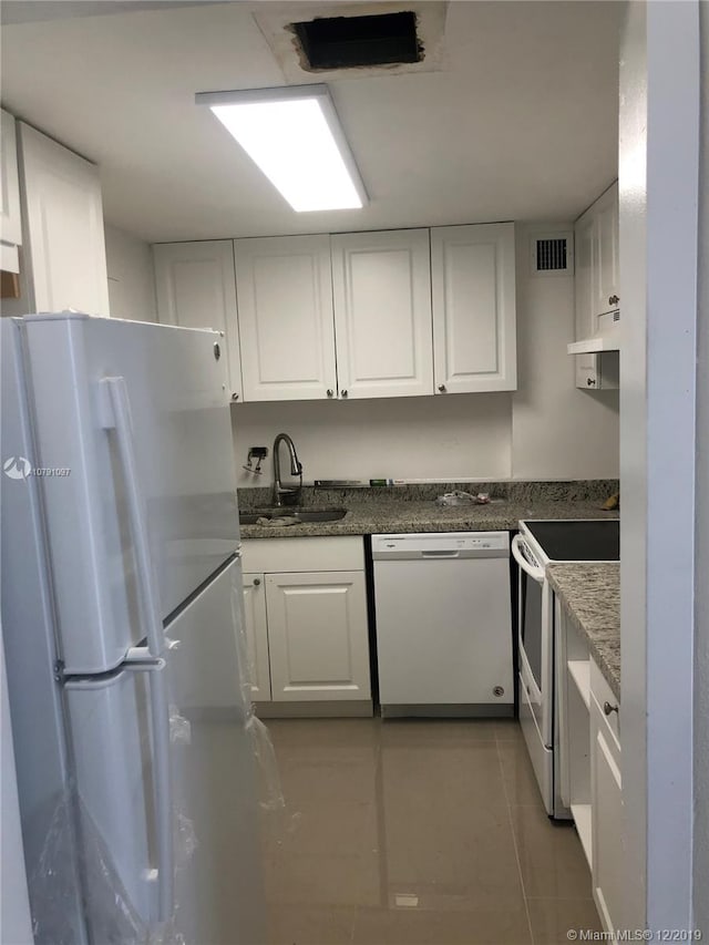 kitchen featuring tile patterned floors, white appliances, sink, dark stone countertops, and white cabinetry