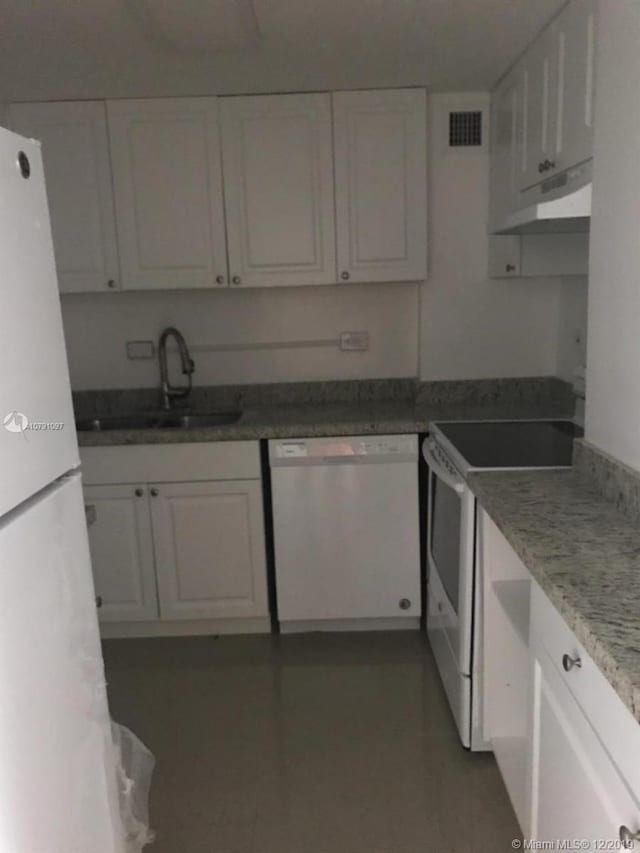 kitchen with white cabinets, white appliances, light stone counters, and sink