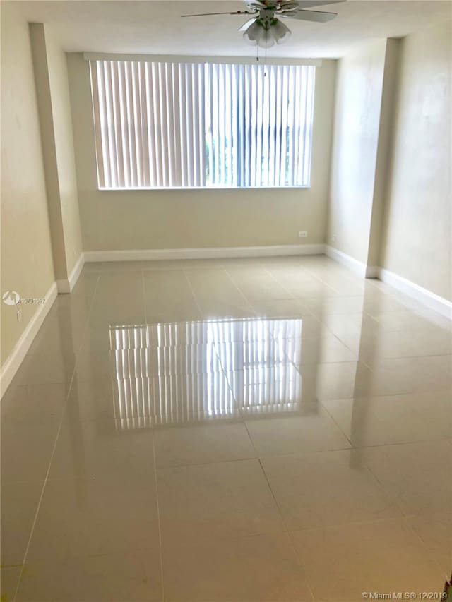 empty room with ceiling fan and light tile patterned floors