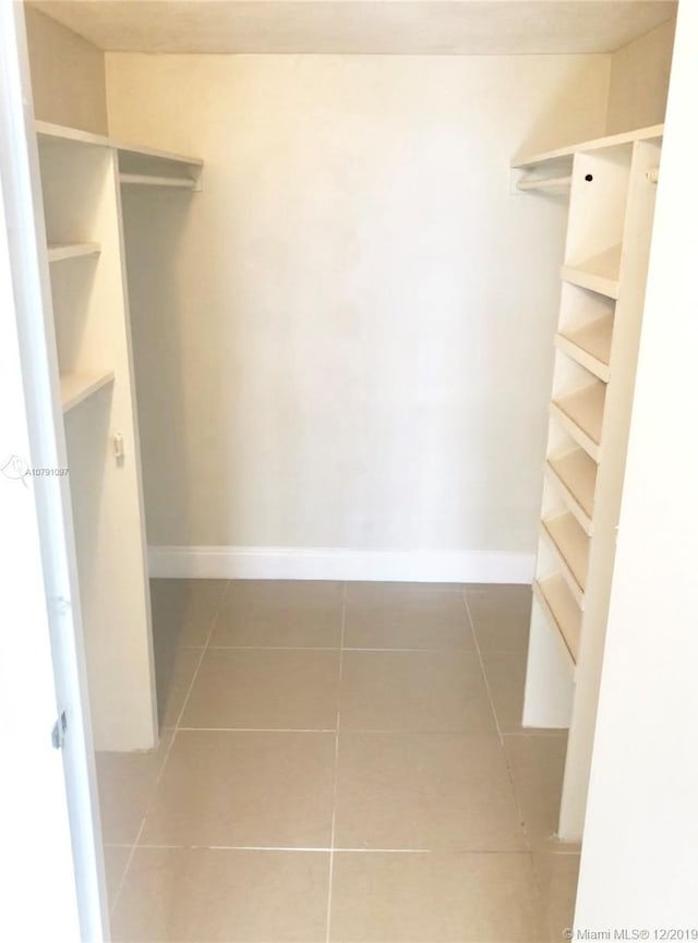 walk in closet featuring dark tile patterned flooring