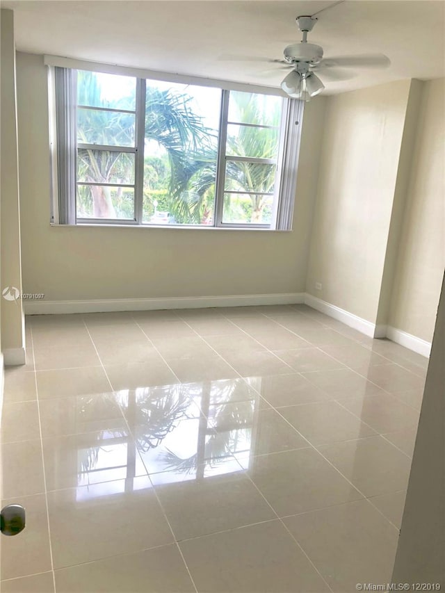 spare room with ceiling fan and tile patterned flooring