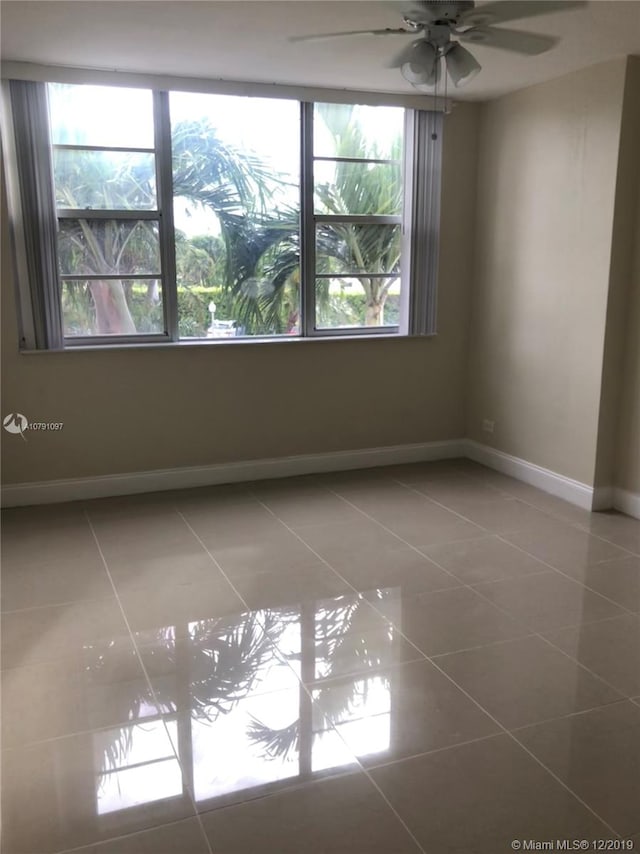 tiled spare room with ceiling fan