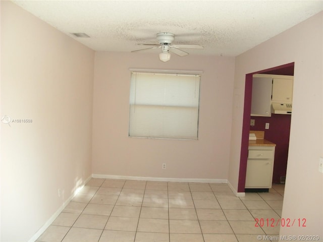 spare room with ceiling fan, light tile patterned flooring, and a textured ceiling