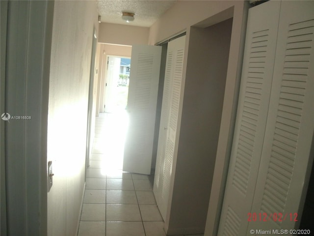 hallway with light tile patterned floors and a textured ceiling