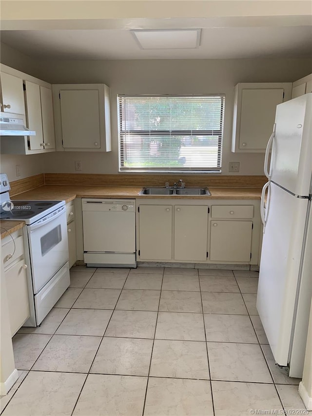 kitchen featuring sink, light tile patterned floors, range hood, white appliances, and white cabinets