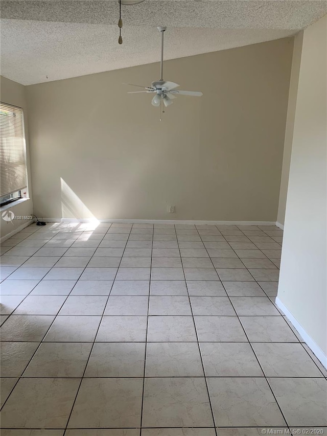 tiled empty room with ceiling fan, lofted ceiling, and a textured ceiling