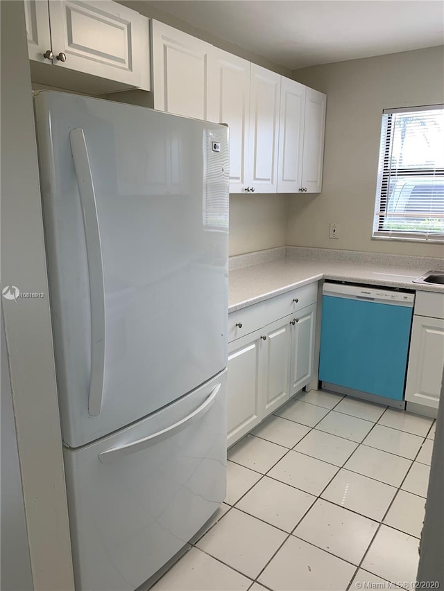 kitchen with dishwashing machine, light tile patterned floors, white fridge, and white cabinetry