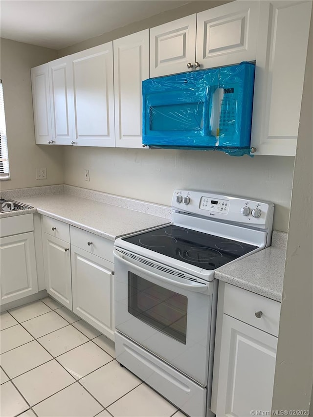 kitchen featuring white cabinetry, electric range, sink, and light tile patterned floors