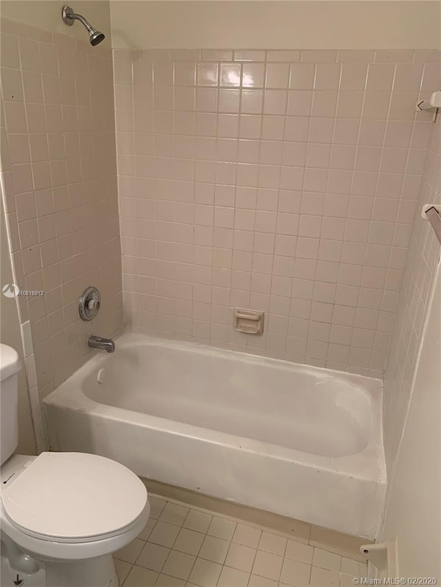 bathroom with tile patterned floors, tiled shower / bath combo, and toilet