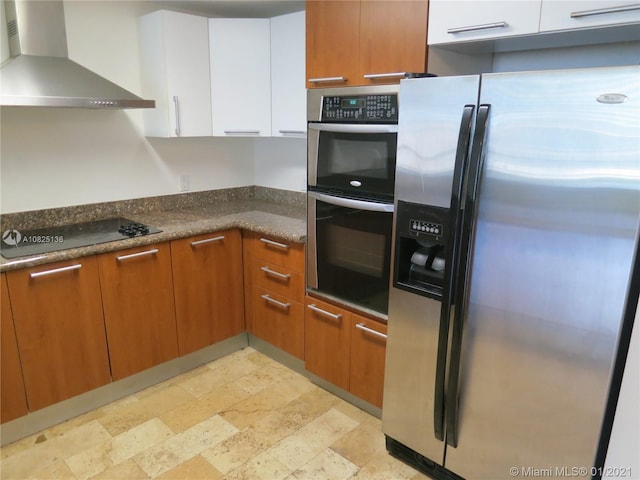 kitchen featuring stainless steel appliances, wall chimney exhaust hood, brown cabinetry, and white cabinets