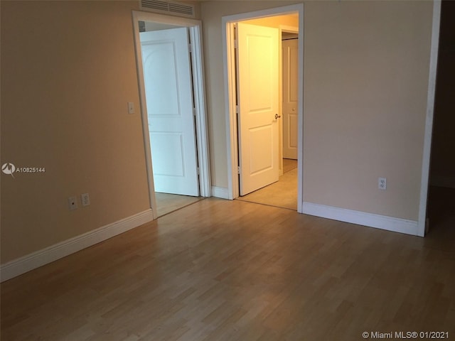 spare room featuring light wood-type flooring, baseboards, and visible vents
