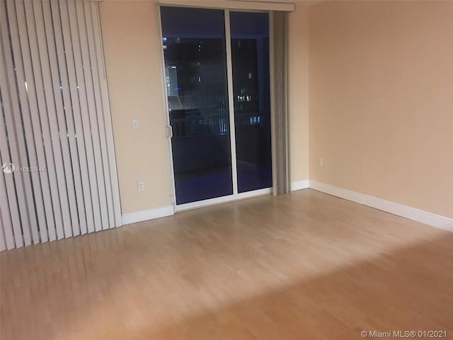 spare room with baseboards and wood finished floors