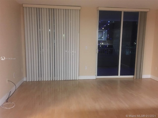 spare room with baseboards and wood finished floors