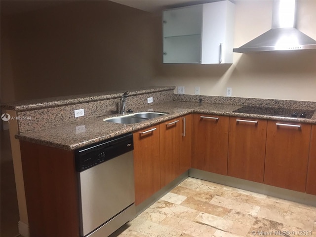 kitchen with dark stone countertops, wall chimney exhaust hood, black electric cooktop, dishwasher, and a sink