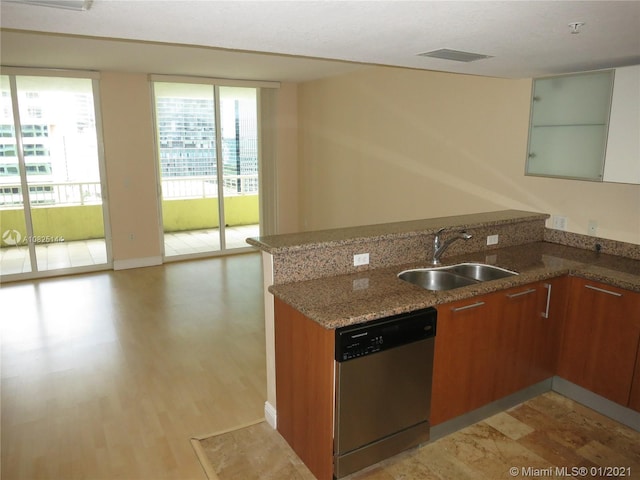 kitchen featuring dishwasher, a sink, a peninsula, brown cabinets, and light stone counters
