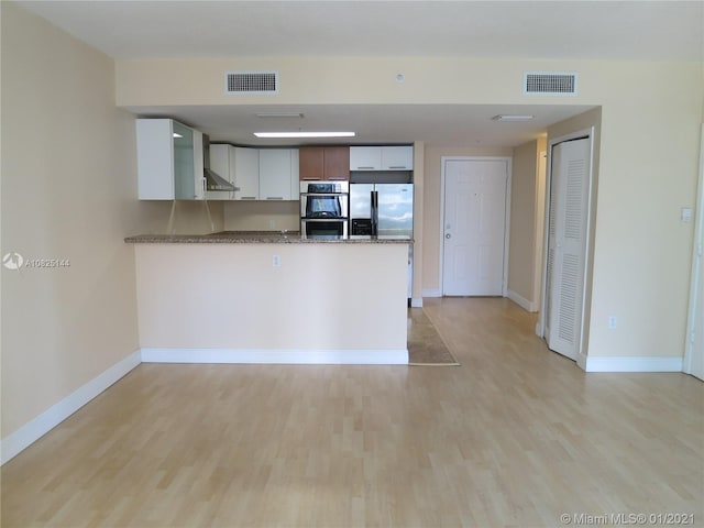 kitchen featuring light wood-style floors, visible vents, appliances with stainless steel finishes, and a peninsula