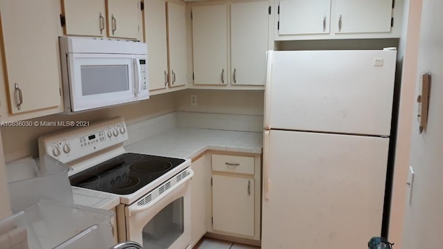 kitchen with cream cabinetry and white appliances