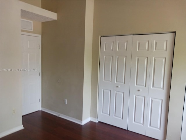 unfurnished bedroom with a closet and dark hardwood / wood-style floors