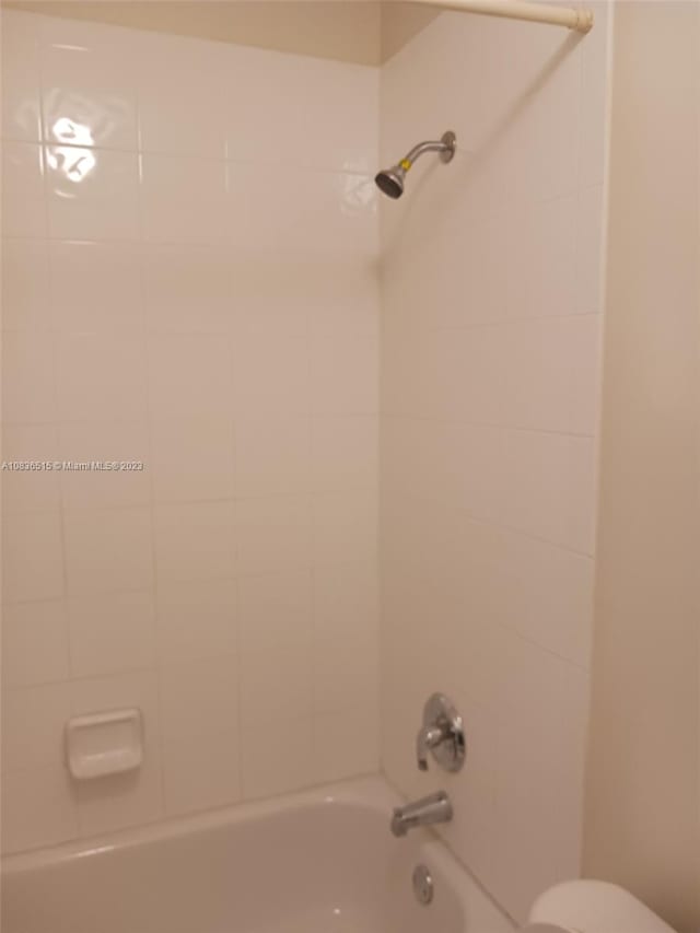 bathroom featuring toilet and tiled shower / bath