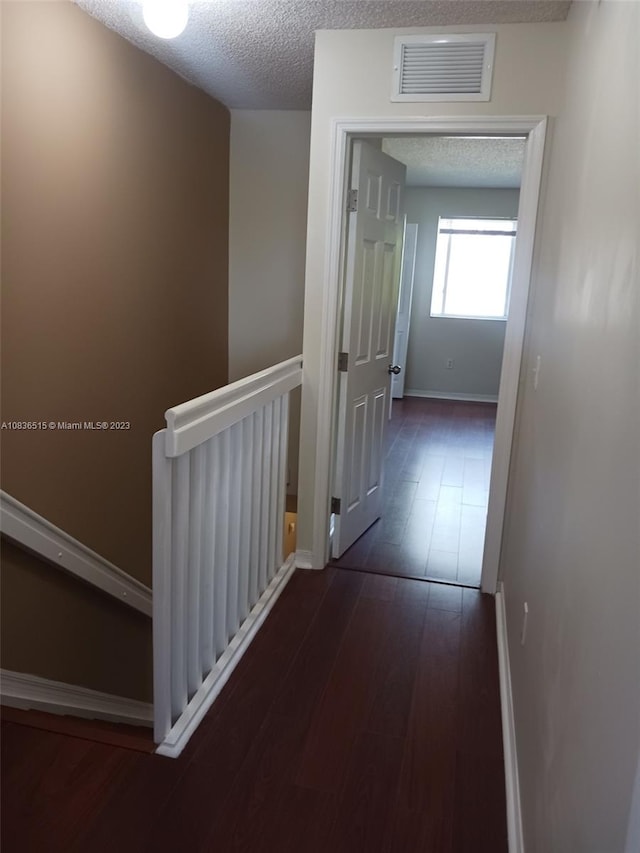 hallway featuring dark hardwood / wood-style floors and a textured ceiling