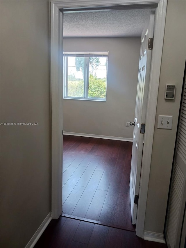 hall featuring a textured ceiling and dark hardwood / wood-style floors